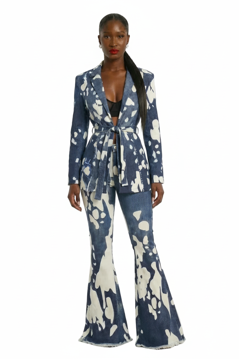 A model stands against a light gray studio background wearing a matching blue and white abstract print blazer and flared pants set.