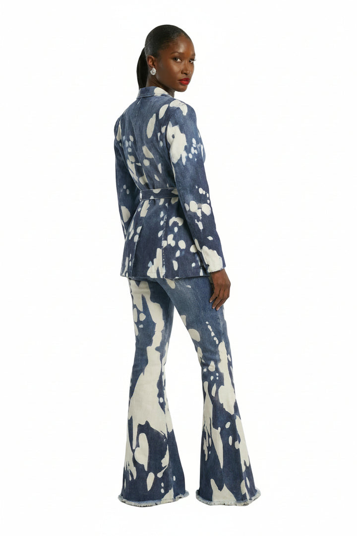 A model is shown from the back wearing a matching blue and white abstract patterned blazer and flared pants set, photographed against a plain light gray studio background.